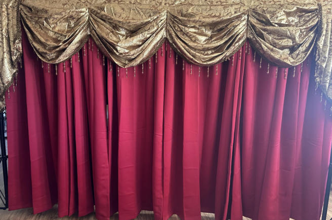 Red and gold theater curtains forming the staged backdrop for a Murder Mystery party